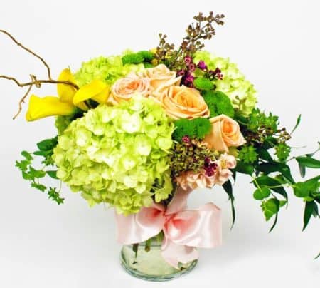 Lime Green Hydrangea's, Yellow Calla Lilies, Peach Roses, Purple Wax Flower fill this beautiful vase finished off with a beautiful bow.