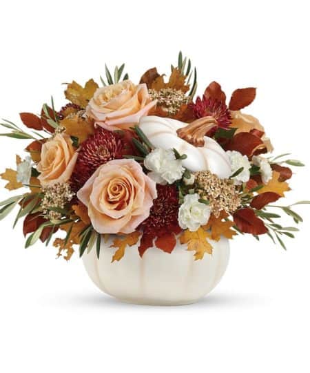 Elegant crème roses blend with the heartwarming hues of autumn in this charming bouquet, artfully arranged in a white lidded pumpkin bowl, a versatile fall decor favorite!